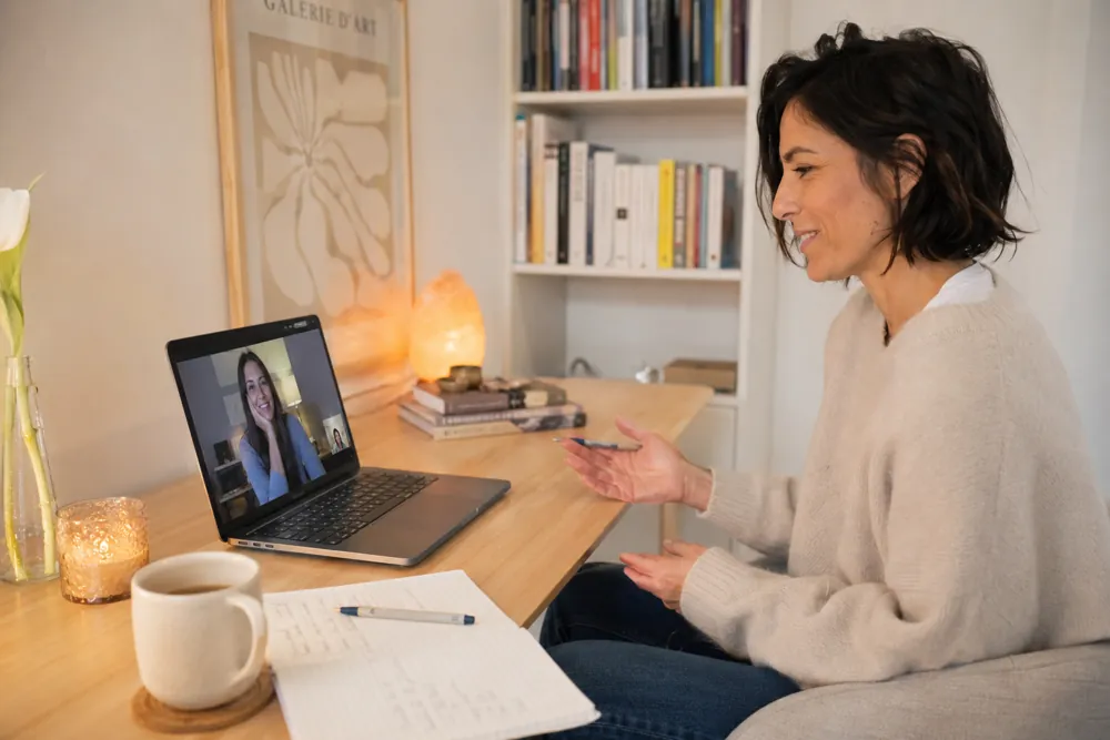 Lara Goded at her desk, smiling during a video call with a client.